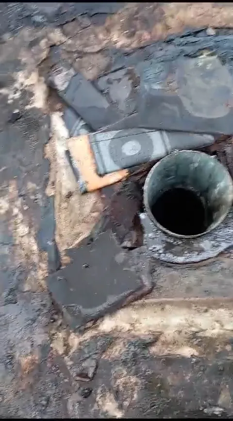 Deschiderea conductei pluviale și straturile hidroizolației expuse în jurul scurgerii.